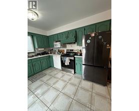 A kitchen with green cabinets and a black fridge.
