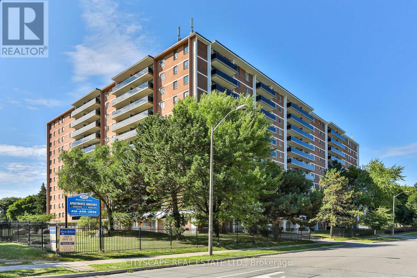 A tall apartment building with a blue sign in front of it.