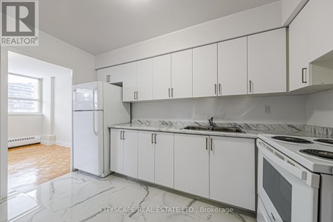A kitchen with white cabinets and appliances is on the market.