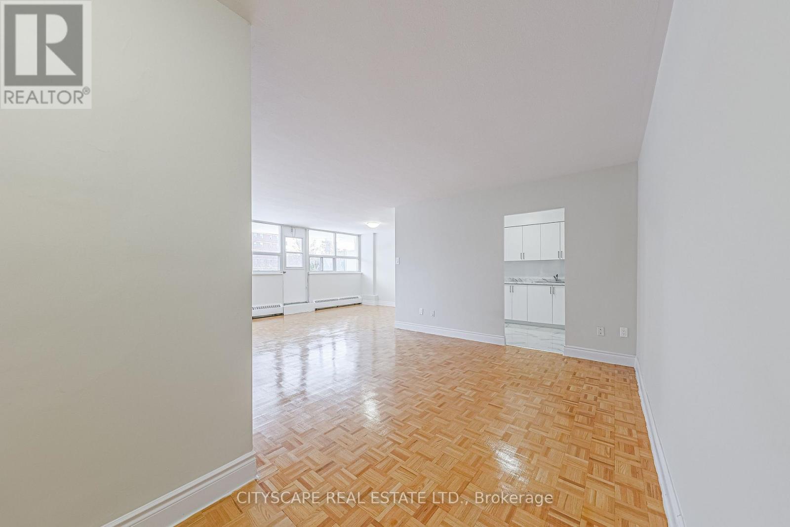 A spacious room with wooden flooring and white walls.