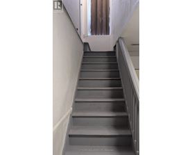 A flight of stairs with a metal railing on the right side.