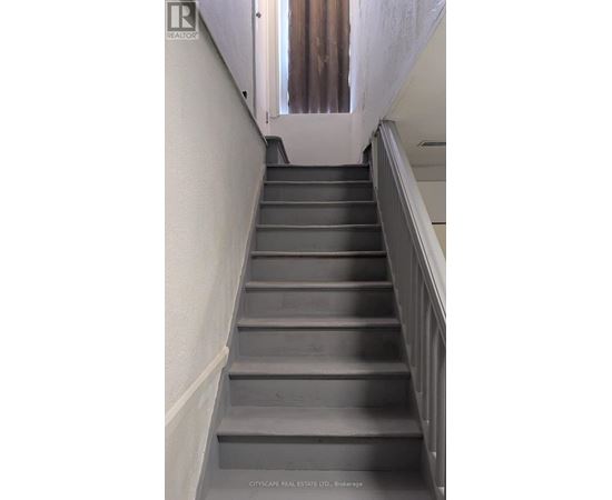 A flight of stairs with a metal railing on the right side.