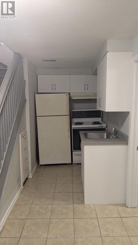 A kitchen with white cabinets and a white fridge.