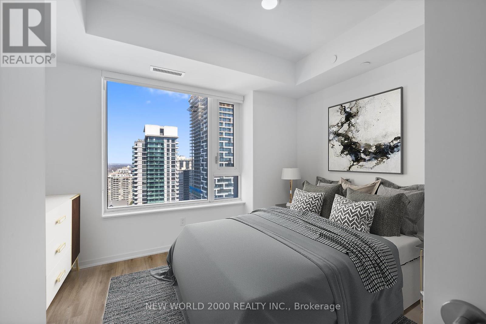 A bedroom with a large bed and a city view through the window.