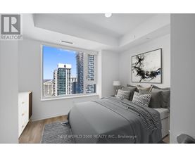 A bedroom with a large bed and a city view through the window.