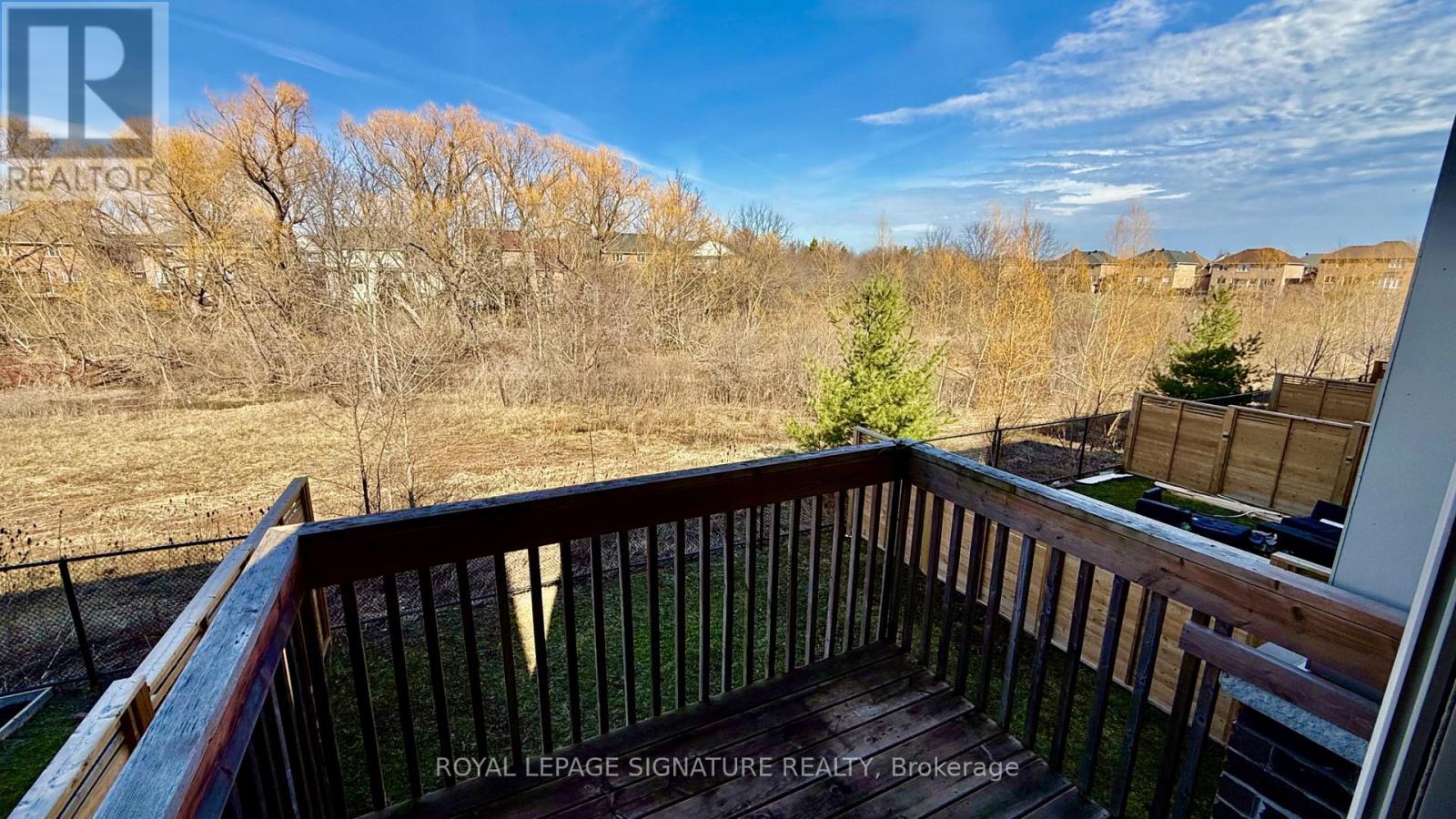 A balcony with a railing and a view of a field and trees.