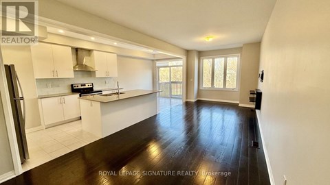 A spacious kitchen with white cabinets and a black fridge.