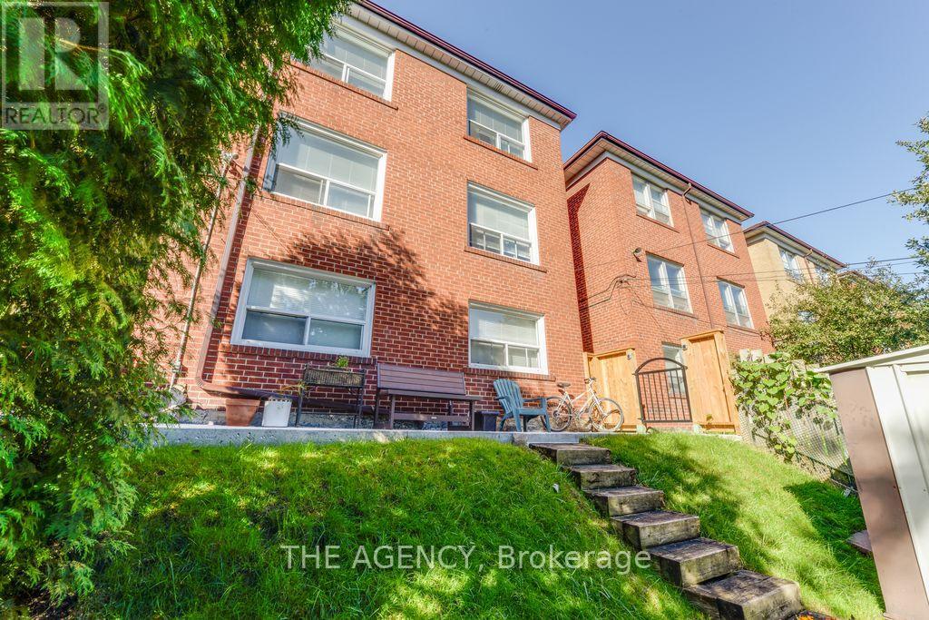 A red brick apartment building with a green lawn in front.
