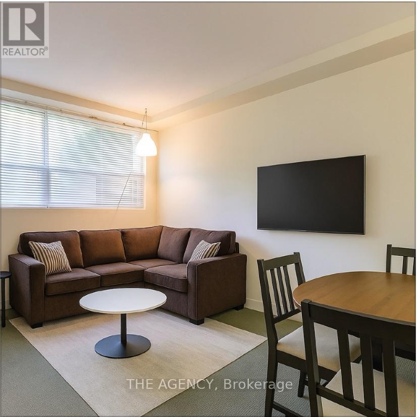 A living room with a brown couch, a white coffee table, and a flat screen TV mounted on the wall.