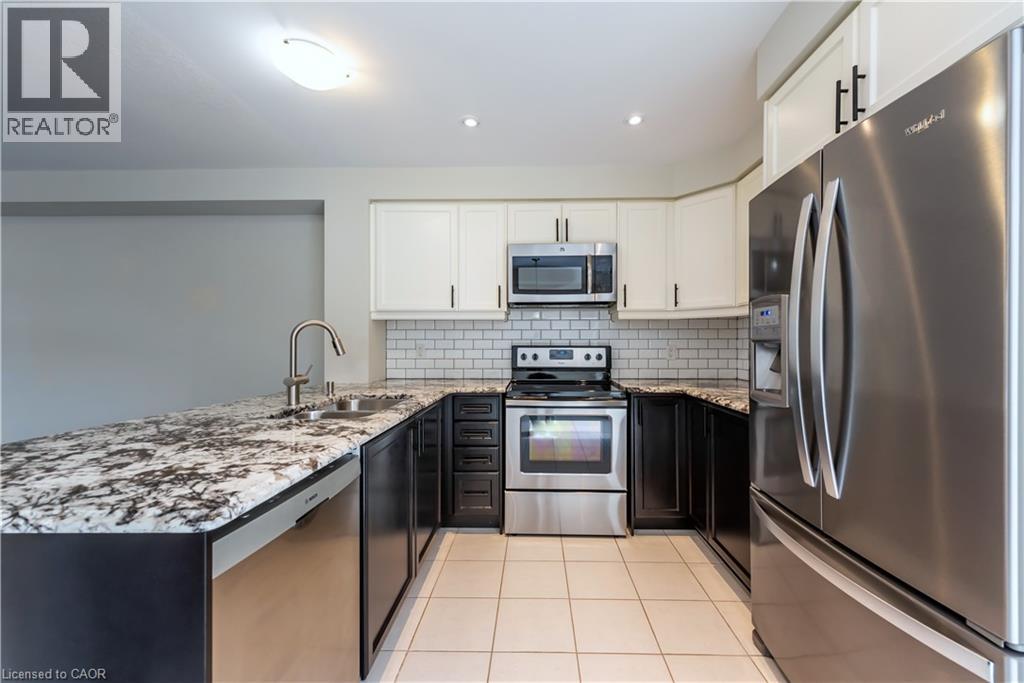A kitchen with a refrigerator, microwave, and oven.