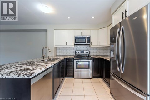 A kitchen with a refrigerator, microwave, and oven.