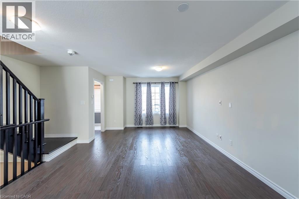 A spacious living room with hardwood floors and a staircase on the left.