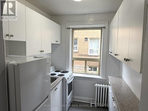A kitchen with white cabinets and a window overlooking a brick building.