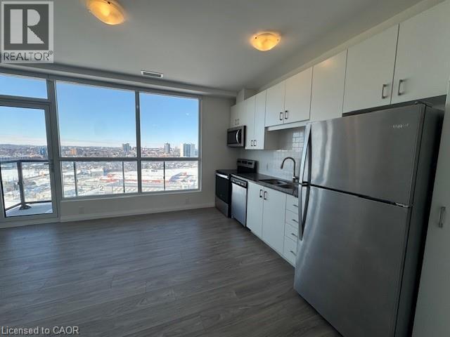 A kitchen with white cabinets and a black fridge.