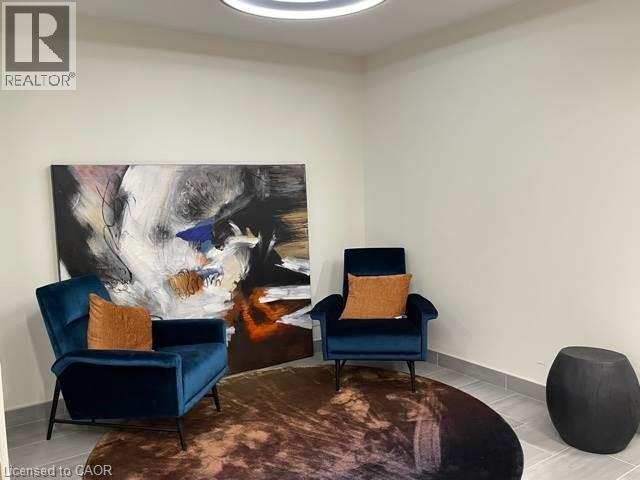 Two blue chairs with orange pillows in front of a painting.