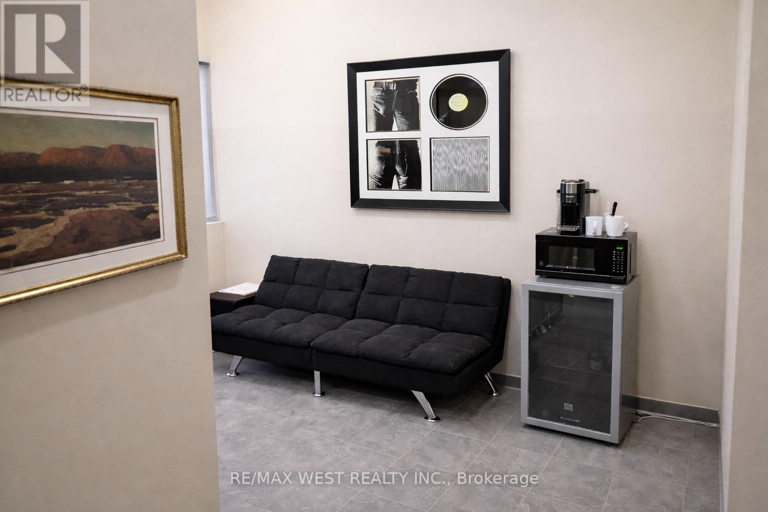 A black sofa sits in a room with a framed picture and a record player.