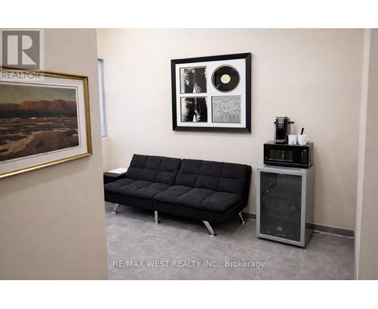A black sofa sits in a room with a framed picture and a record player.
