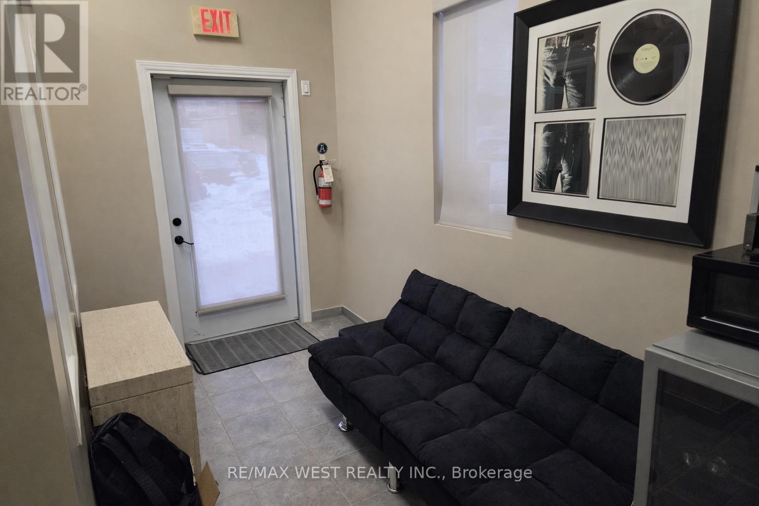 A brokerage office with a black couch and a framed record on the wall.