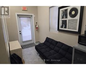 A brokerage office with a black couch and a framed record on the wall.