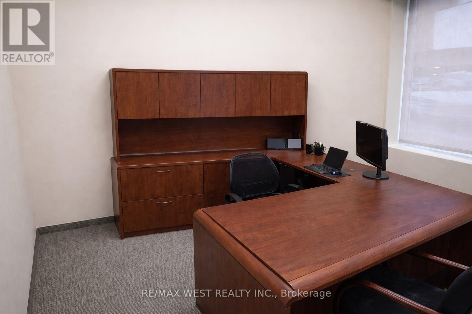 A brown desk with a computer and a chair in a room.