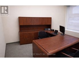 A brown desk with a computer and a chair in a room.