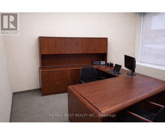 A brown desk with a computer and a chair in a room.
