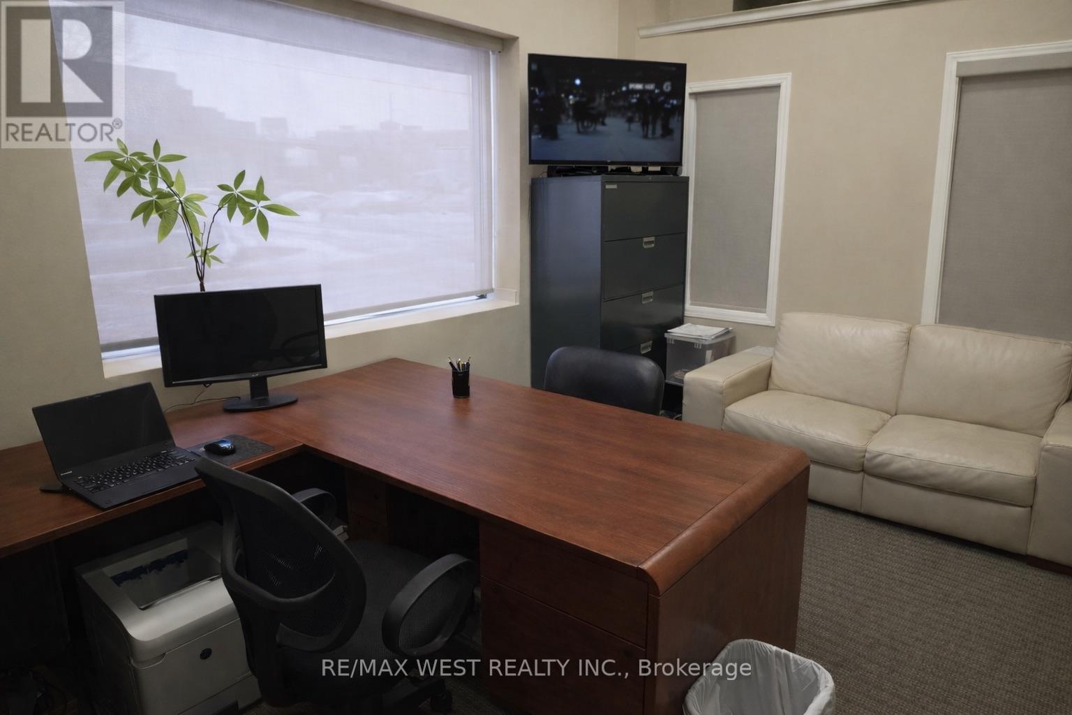 A REALTOR sign is on the corner of a desk in an office.