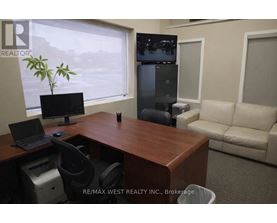 A REALTOR sign is on the corner of a desk in an office.