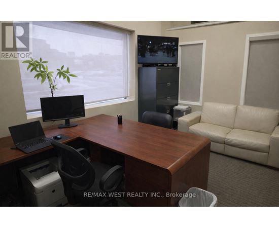 A REALTOR sign is on the corner of a desk in an office.