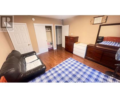 A living room with a black leather chair and a blue and white checkered rug.
