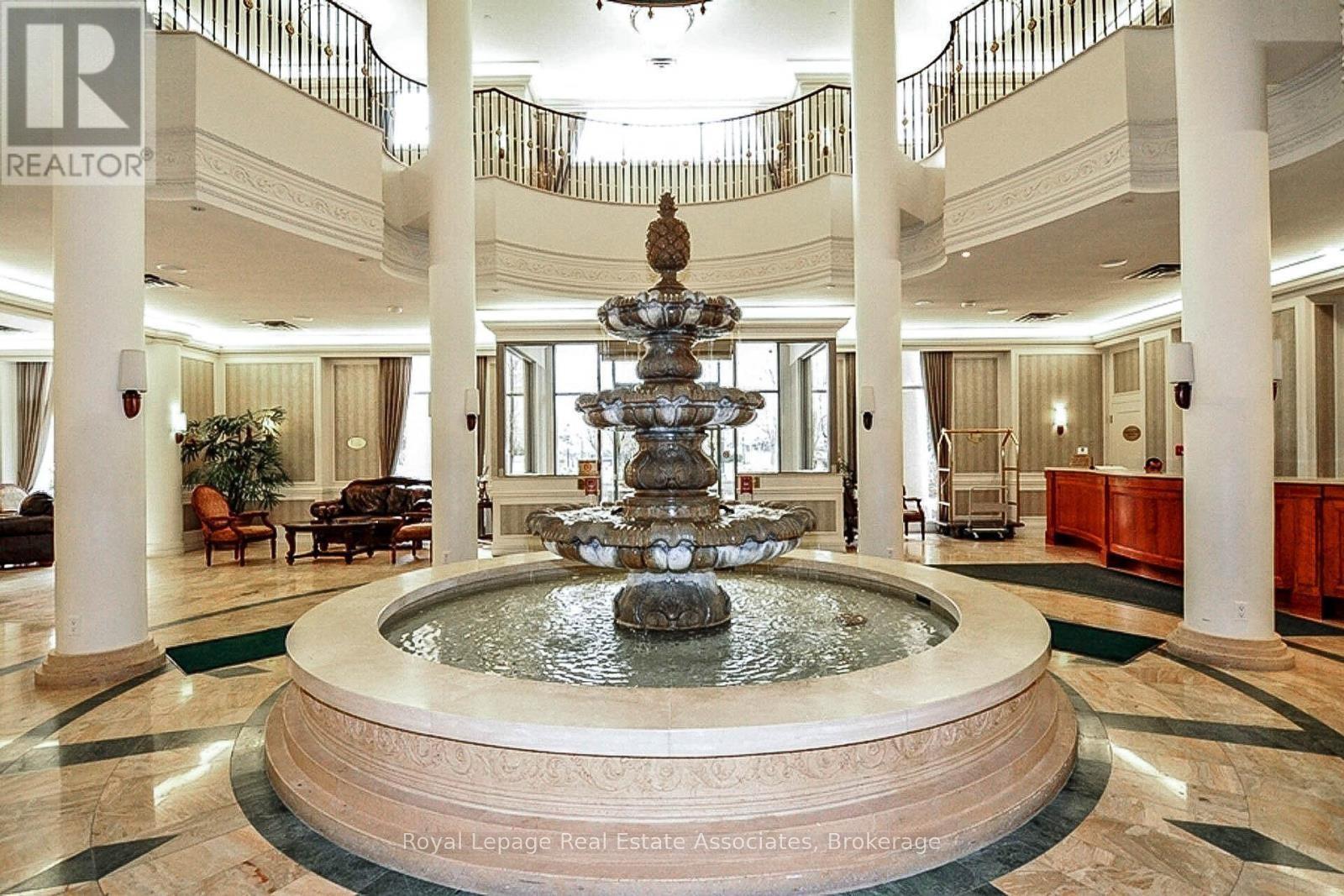 A large, ornate fountain is the centerpiece of a spacious lobby.
