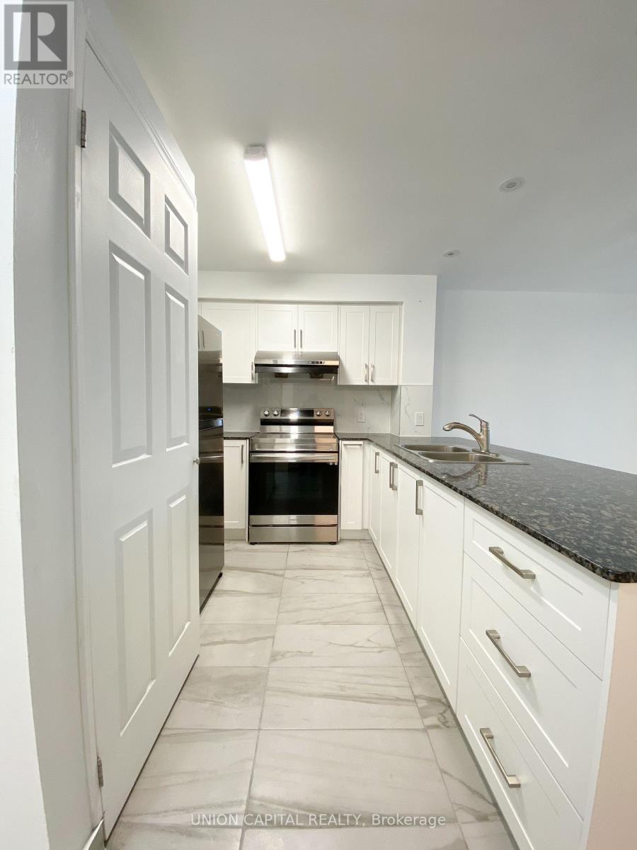 A kitchen with white cabinets and a black counter top.