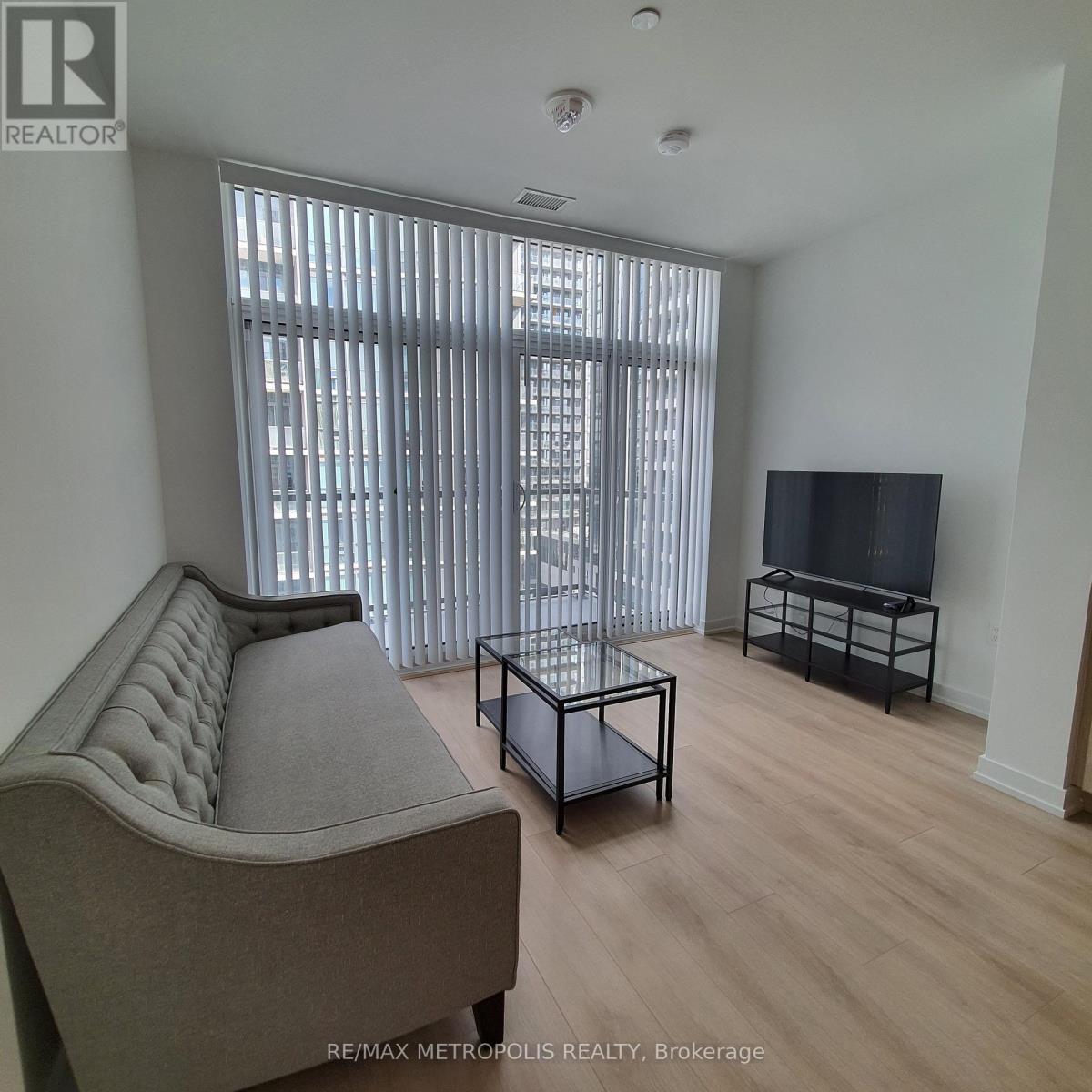 A living room with a grey sofa, a black coffee table, and a flat screen TV.