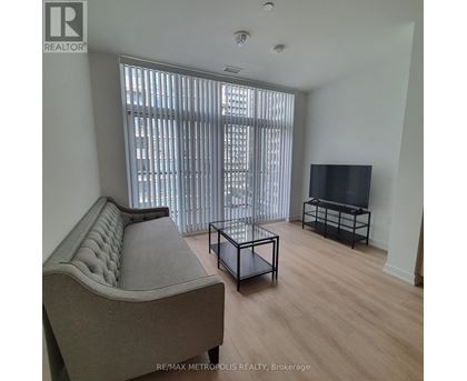 A living room with a grey sofa, a black coffee table, and a flat screen TV.