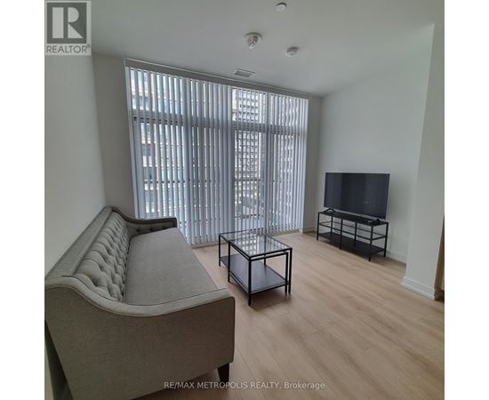 A living room with a grey sofa, a black coffee table, and a flat screen TV.