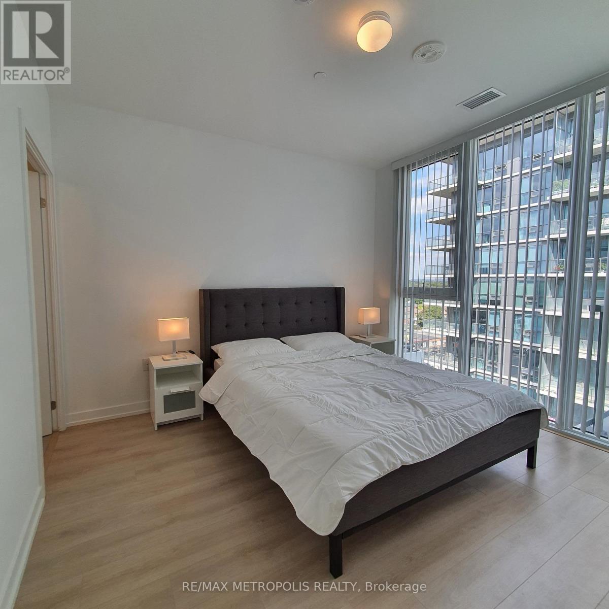 A bedroom with a large bed and a window overlooking a cityscape.