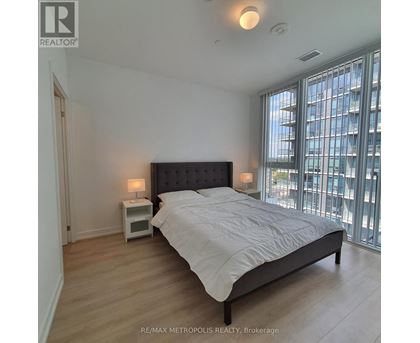 A bedroom with a large bed and a window overlooking a cityscape.