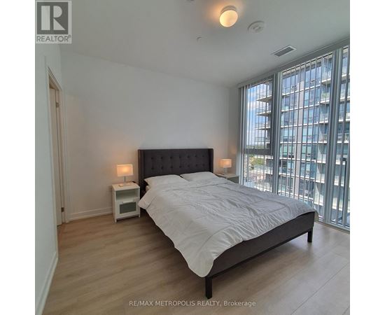 A bedroom with a large bed and a window overlooking a cityscape.