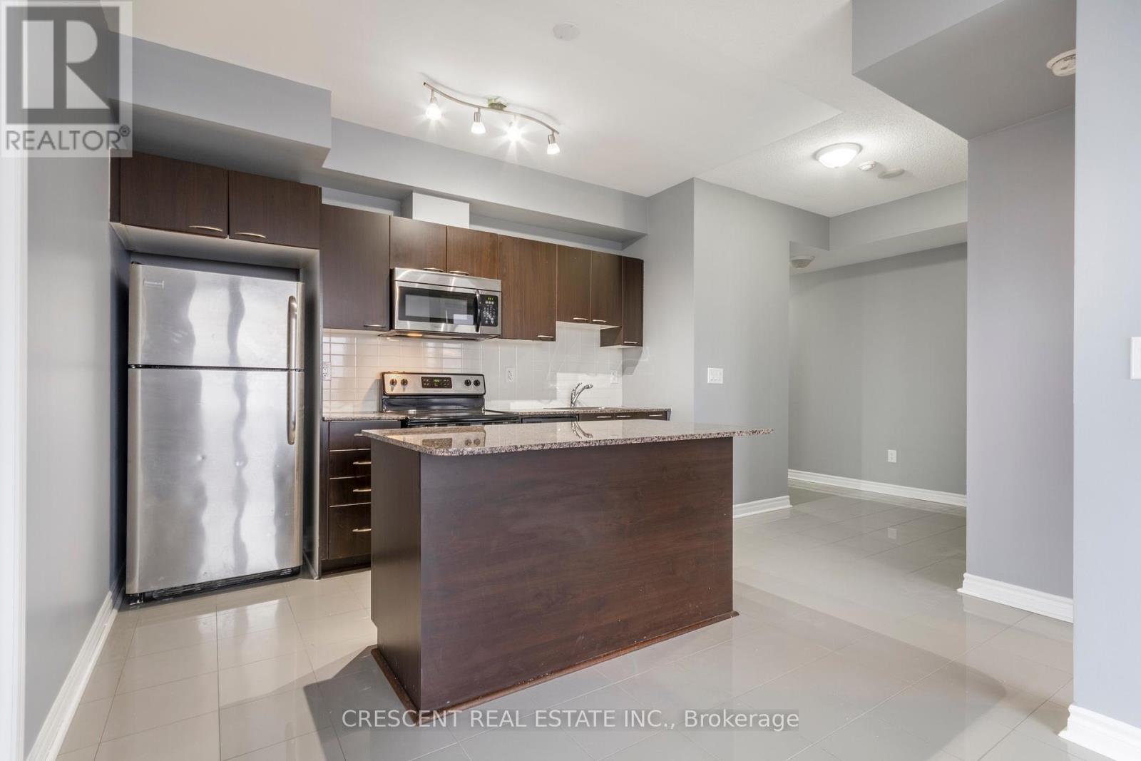 A modern kitchen with a refrigerator, microwave, and oven.