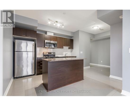 A modern kitchen with a refrigerator, microwave, and oven.