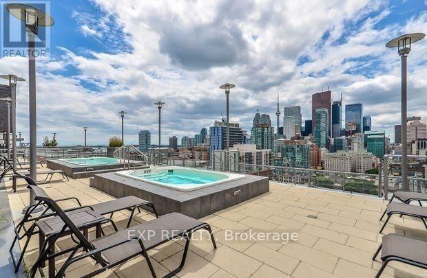 A rooftop with a pool and chairs overlooking a city skyline.