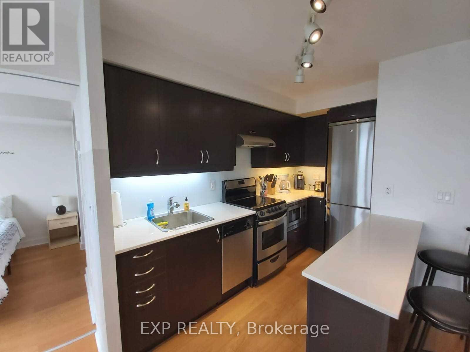 A kitchen with black cabinets and stainless steel appliances.