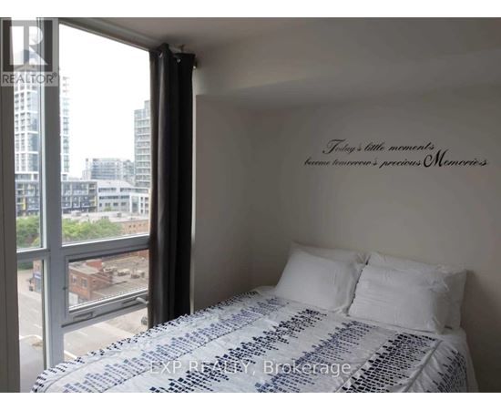 A bedroom with a large bed and a window overlooking a cityscape.