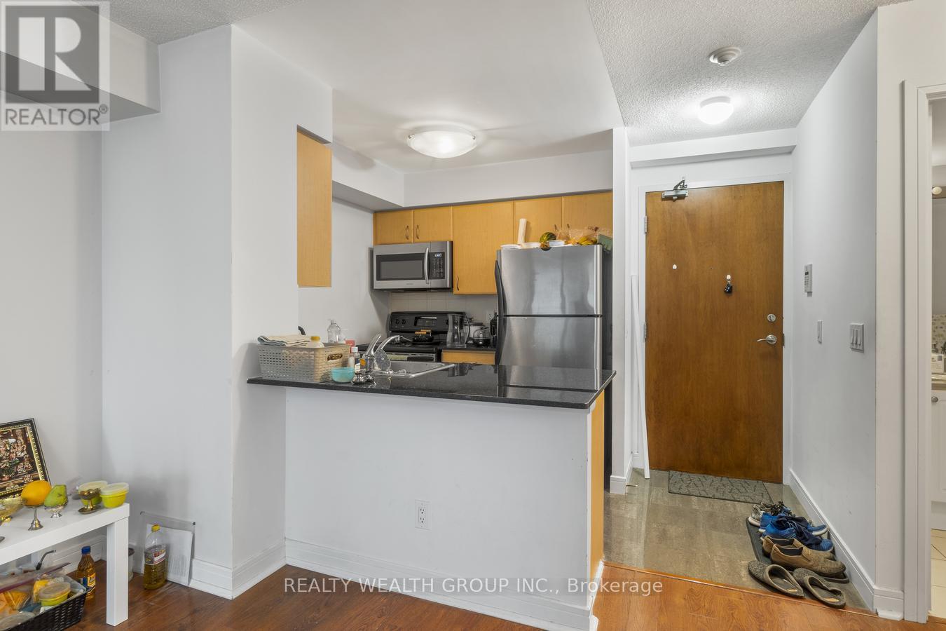 A kitchen with a refrigerator, microwave, and sink.