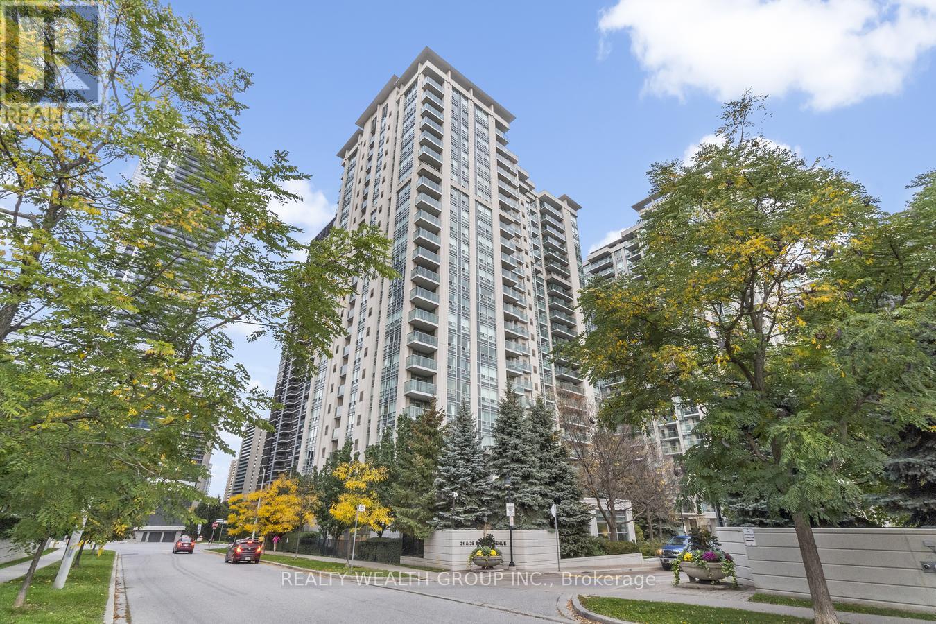 A tall building with a lot of windows is surrounded by trees with yellow leaves.