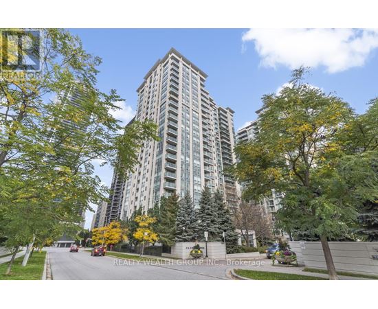 A tall building with a lot of windows is surrounded by trees with yellow leaves.