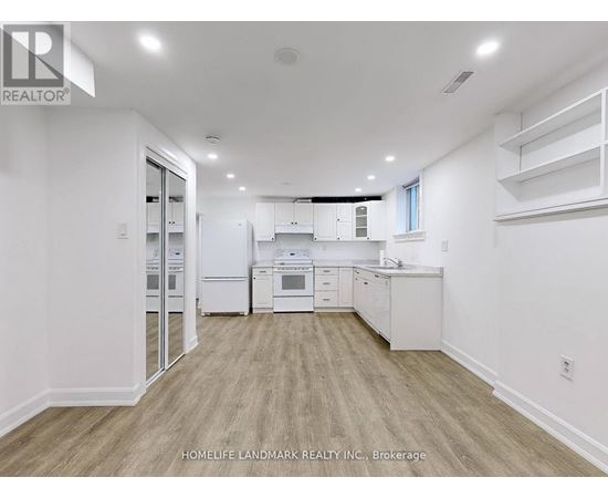 A well-lit, spacious kitchen with white appliances and wooden flooring.