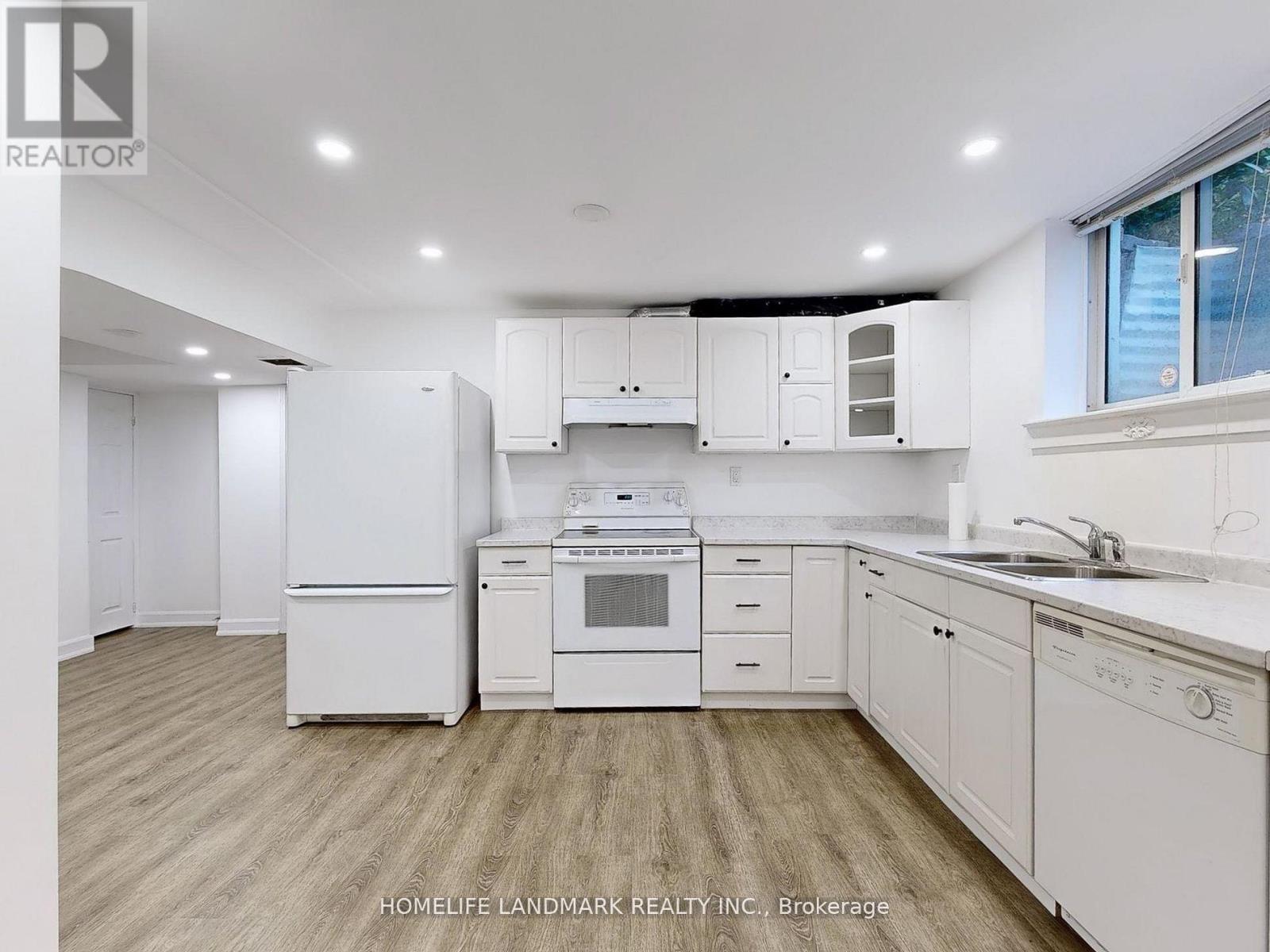 A white kitchen with wooden floors and white appliances.