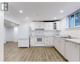 A white kitchen with wooden floors and white appliances.