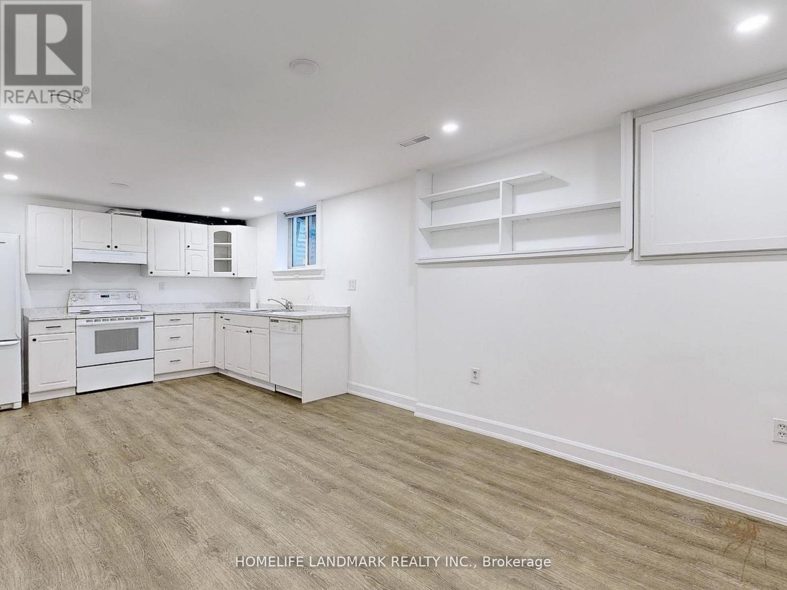 A spacious kitchen with white cabinets and a wooden floor.
